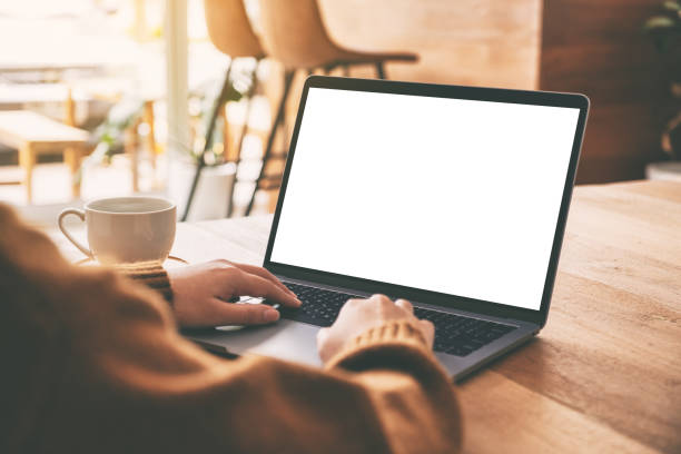istock Mockup image of a woman using and typing on laptop computer with blank white screen and coffee cup on wooden table 1149180083