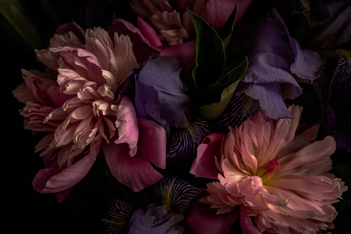 Dark-toned photo of lilies and peonies in vase.