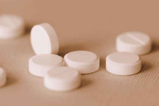 istock White tablets scattered on a surface close up. Brown color toned 1149192483