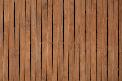 Section of a dark gray wooden fence with faded and peeling paint.