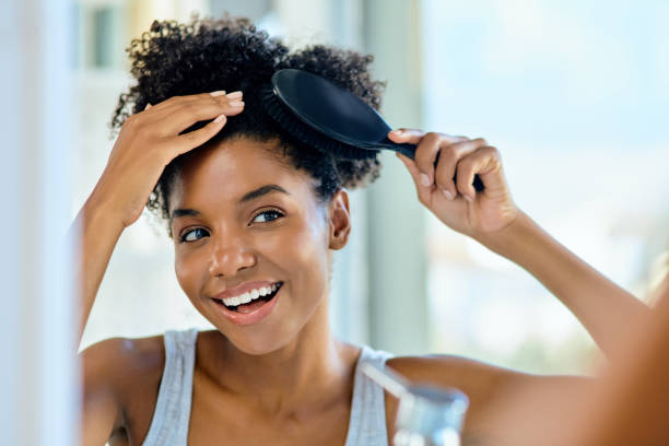 Brushing her way to an awesome hair day Shot of an attractive young woman brushing her hair during her morning beauty routine at home brushing hair stock pictures, royalty-free photos & images