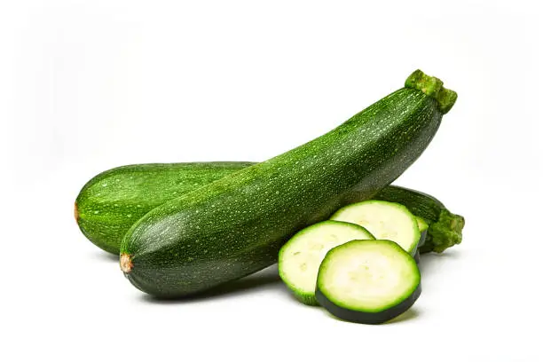 Photo of Fresh whole and sliced zucchini isolated on white background. From top view. Courgette zucchini cut into slices