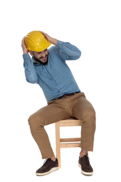 istock scared man sitting with hands on yellow helmet 1149202011