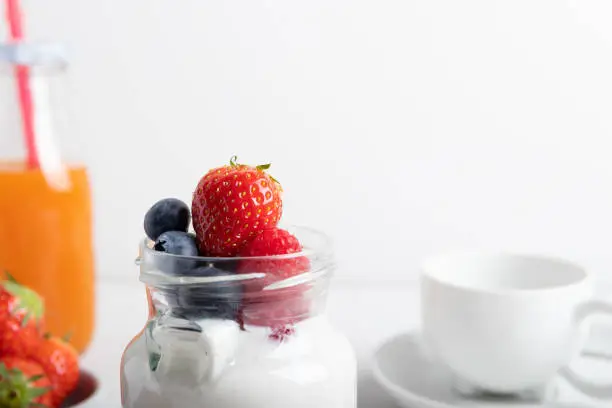yogurt with strawberries, raspberries and blueberries on a breakfast table. Isolated on a white background