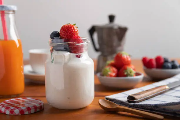yogurt with strawberries, raspberries and blueberries on a breakfast table.