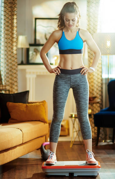 istock woman in modern house training using vibration power plate 1149204336