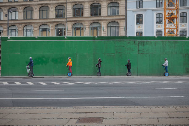Copenhagen, Denmark – May 1, 2019:  Tourists on sightseeing in front of a green fence.