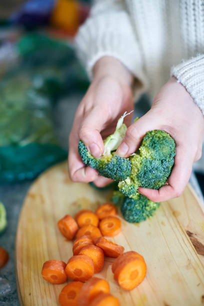 istock Female hands pull apart head of fresh broccoli in kitchen 1149207160