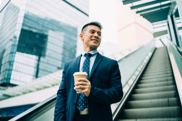 istock Smiling businessman moving down on escalator at workplace 1149207251