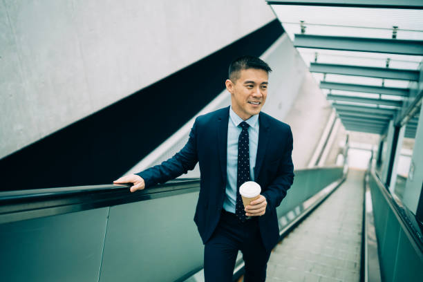 istock Businessman holding coffee cup and moving up on escalator 1149207259