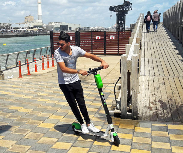 Fun and freedon with an Electric Scooter in Tel Aviv Young man riding a LIME electric scooter in the new Promenade of Tel Aviv. Due to good weather and sun most of the year, Electric scooters are making their way in Tel Aviv. 
"Lime.S" has more that 500 electric scooters that users can pick up and leave on city streets, without having to lock them up. The scooters are accessed by smartphones, and paid for by credit cards kept on file. lime scooter stock pictures, royalty-free photos & images