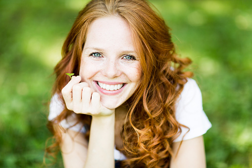 young beautiful woman with beautiful smile, red hair, blue eyes, freckles, lucky clover, jeans pants, leisure, holiday, relax, joyful, joy