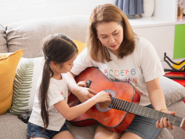 istock Mother playing guitar with daughter in room 1149216020