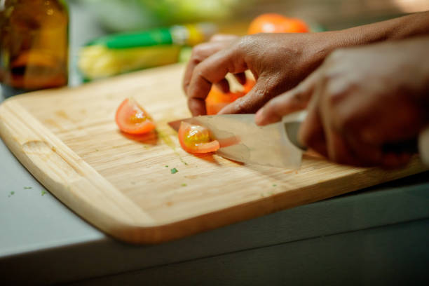 Close up shot of chopping tomato on wooden board