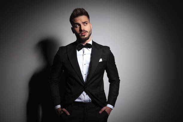 istock elegant guy in black tuxedo holding hands in pockets and beeing curious 1149218089