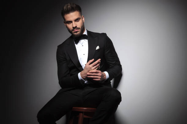 istock seated man in black tuxedo holding hands together 1149220163