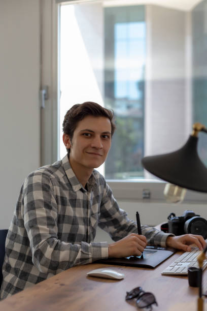 istock Young male graphic designer or photographer smiling to camera while working on computer using digital tablet at office. 1149220662