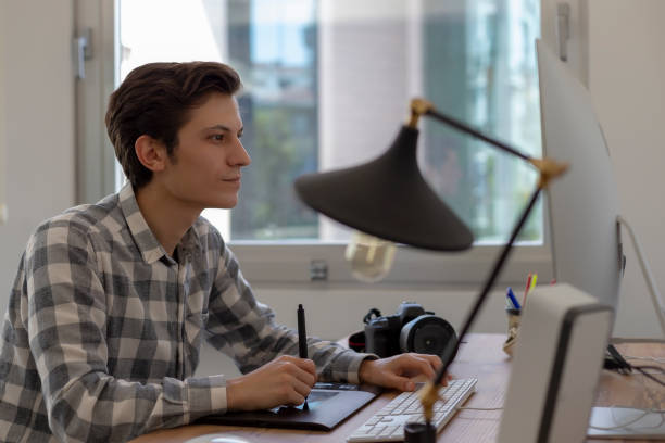 istock Young male graphic designer or photographer working on computer using digital tablet at office. 1149220703