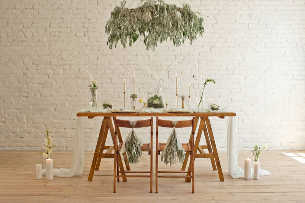 Boho wedding table setting, rustic decorations, gold and blue details, wooden table, bokeh. Luxury wedding decor. Monstera leaves and orchid flowers