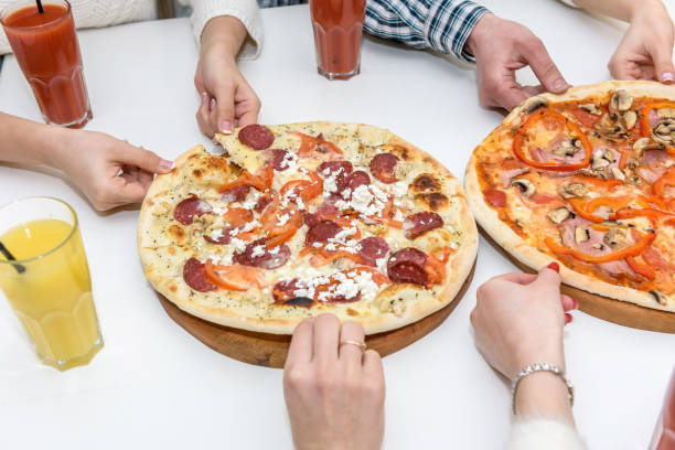 istock Tasty pizza with human hands on the table close up 1149225766