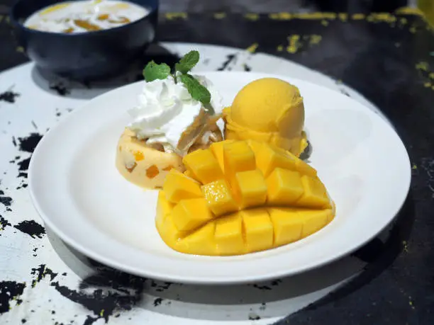 Photo of Yummy mango panna cotta and whipped cream with sliced fresh ripe mango and mango sorbet icecream.