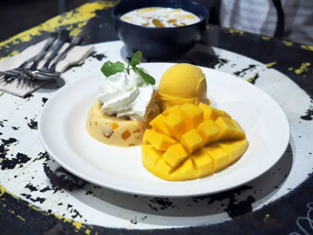 Photo of Yummy mango panna cotta and whipped cream with sliced fresh ripe mango and mango sorbet icecream.