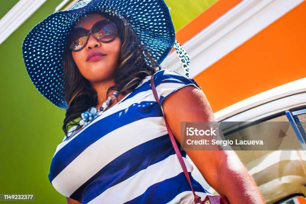 Close Up Of A Beautiful African Woman In A Blue And White Striped Dress In Front Of A Vintage Volkswagen Beetle And Traditional Homes Of Bokaap Cape Town Stock Photo - Download Image Now