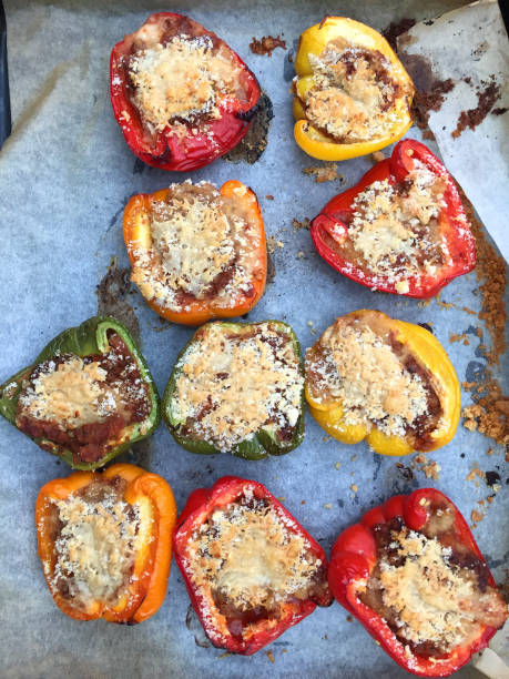 immagine di peperoni ripieni con salsa vegetariana bolognese, parmigiano e pangrattato, peperoni / capsicum a semaforo rossi, gialli e verdi cotti in forno per mangiare sano cibo dietetico, su teglia in polvere in cucina, sul tavolo da pranzo - stuffed stuffed pepper pepper bell pepper foto e immagini stock