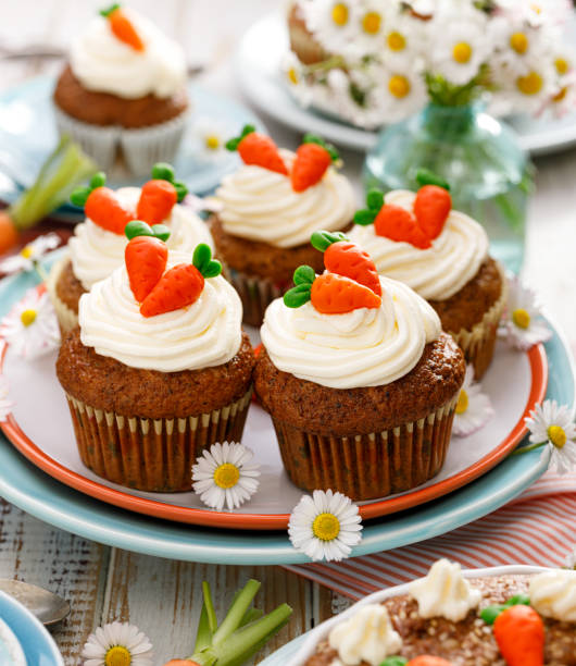 Carrot cupcakes with mascarpone cream decorated with marzipan carrots on a plate.