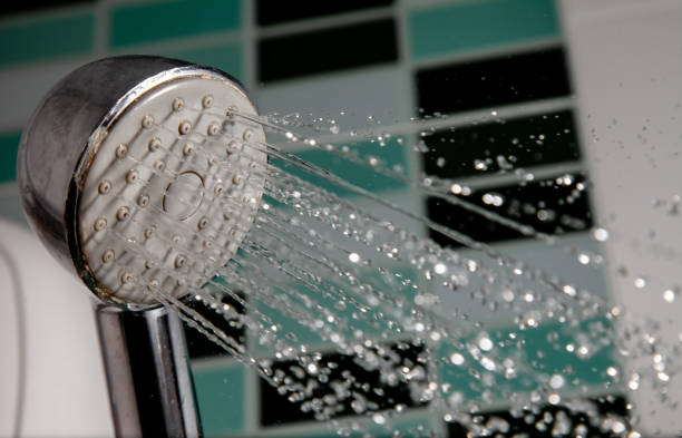 istock Shower head splashing water with water drops flowing in bathroom. 1149239020