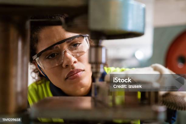 Mid Adult Engineer Using Yoke Machine In Factory Stock Photo - Download Image Now - Engineer, Women, Close-up