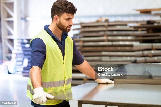 Serious Engineer Adjusting Metal Sheet In Industry Stock Photo - Download Image Now - 20-24 Years, Adjusting, Adult