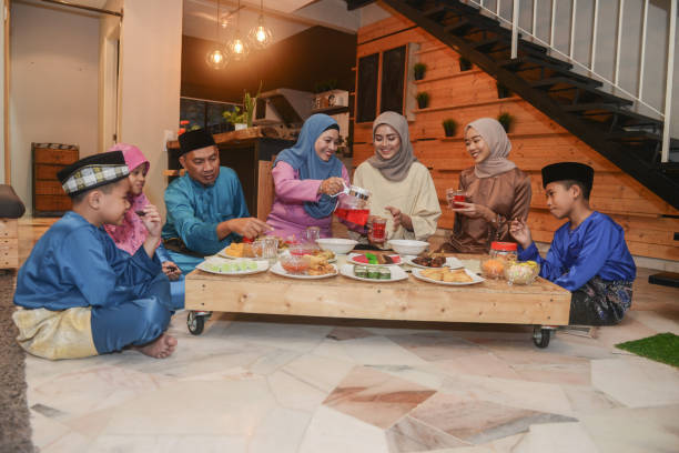 Malaysian Muslim family celebrating Eid-Ul-Fitr at home Malaysian Muslim family celebrating Eid-Ul-Fitr at home hari raya family stock pictures, royalty-free photos & images