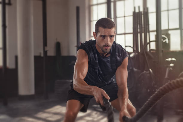 man doing cross training exercise with rope - treino imagens e fotografias de stock