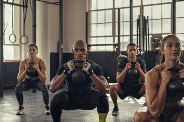 persone di fitness accovacciate con kettlebell - cross training foto e immagini stock