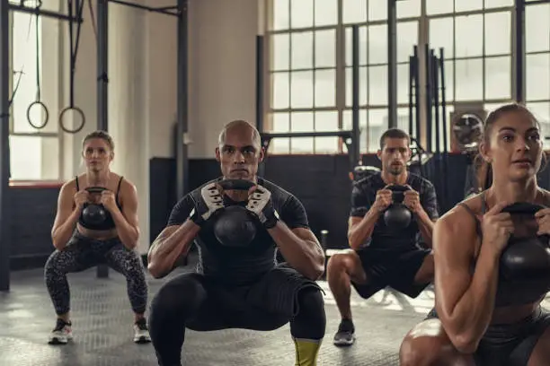 Photo of Fitness people squatting with kettlebell