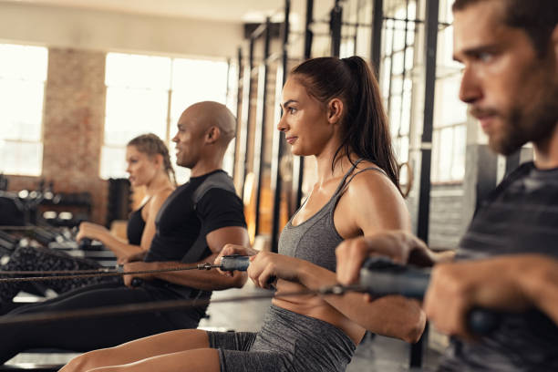 fitness class training on rowing machine - people in a row group of people in a row togetherness imagens e fotografias de stock
