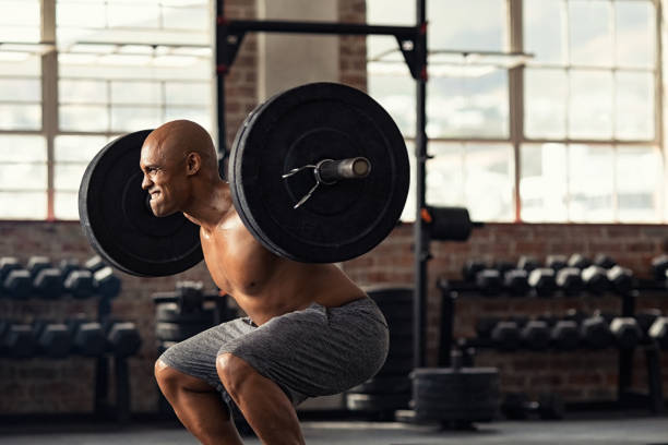 uomo forte maturo che solleva pesi durante l'allenamento incrociato - crouching barbell weightlifting weight training foto e immagini stock