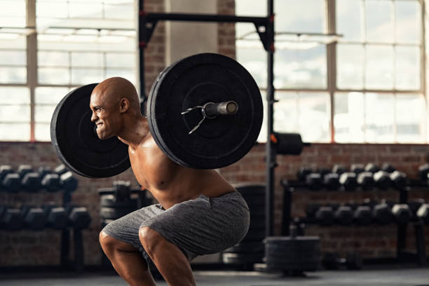 成熟した強い男がクロストレーニングで重みを持ち上げる - weight training crouching barbell weightlifting ストックフォトと画像