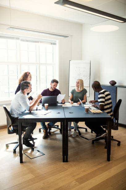istock Group of diverse designers talking together around an office table 1149244360