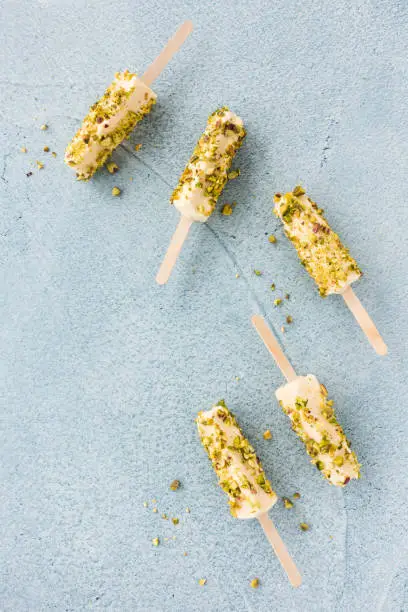 Top view of homemade mango and pistachio kulfi popsicles on blue cement background with copy space. Top view.