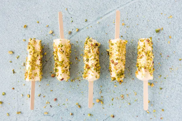 Mango and pistachio kulfi lollies on blue cement background. Top view.