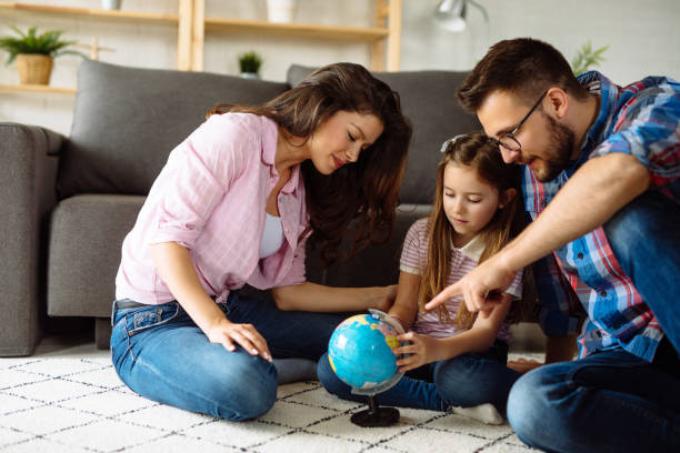 parents and daughter looking at globe in living room - earth globe mother child imagens e fotografias de stock