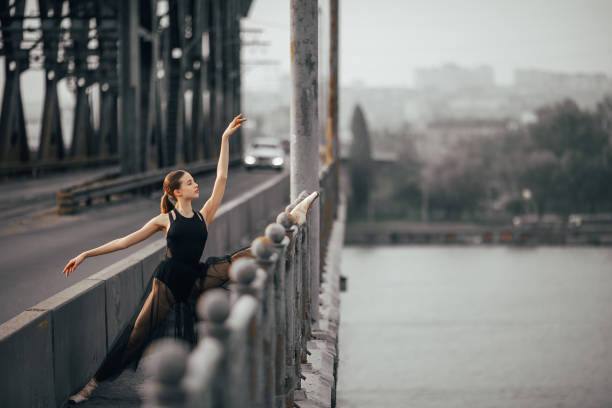 istock Ballerina sitting in twine pose on the bridge through the river. 1149247433