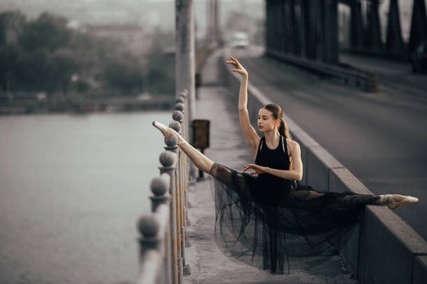 istock Ballerina sitting in twine pose on the bridge through the river. 1149247461