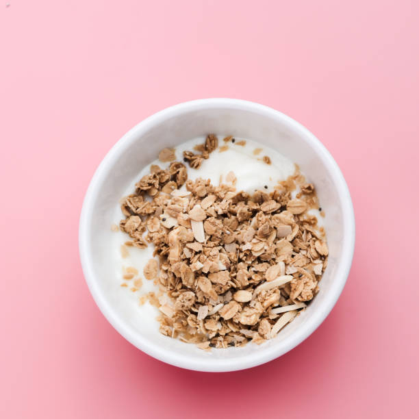 istock Whole grains on yogurt in white bowl, pink background. 1149247694