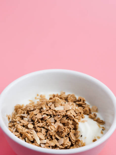 istock Whole grains on yogurt in white bowl, pink background. 1149248540