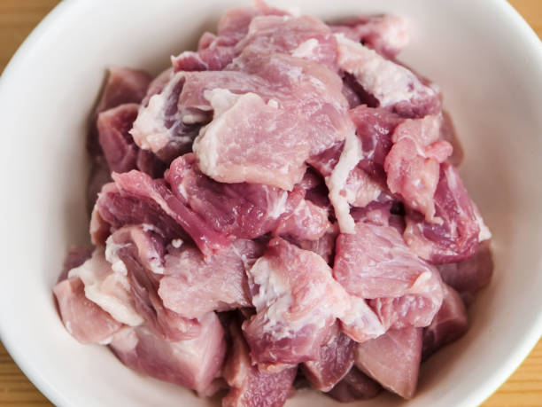 istock Cutting pork meat in bowl on table. 1149255580