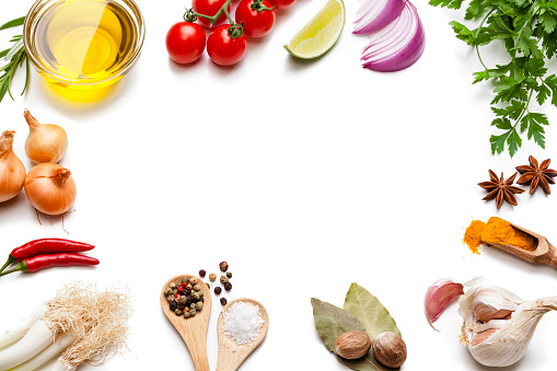 Cooking and seasoning backgrounds: High angle view of a white background with multi colored vegetables, herbs and spices placed all around the border making a frame and leaving a useful copy space for text and/or logo at the center. The composition includes olive oil, cherry tomatoes, lime slice, red onion, parsley, star anise, curry powder, garlic, bay leaves, nutmeg, salt, pepper, chili pepper, and gold onions. High key DSRL studio photo taken with Canon EOS 5D Mk II and Canon EF 100mm f/2.8L Macro IS USM.