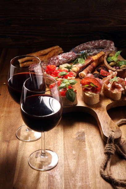 istock Traditional italian antipasto bruschetta appetizer with cherry tomatoes, cream cheese, basil leaves and balsamic vinegar on cutting board with prosciutto, salami, cheese 1149258801
